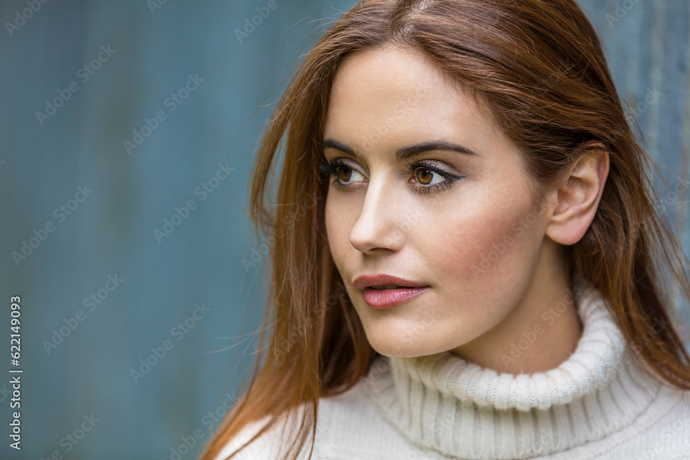 Naklejka premium Outdoor portrait of beautiful girl or young woman with red hair wearing a white jumper