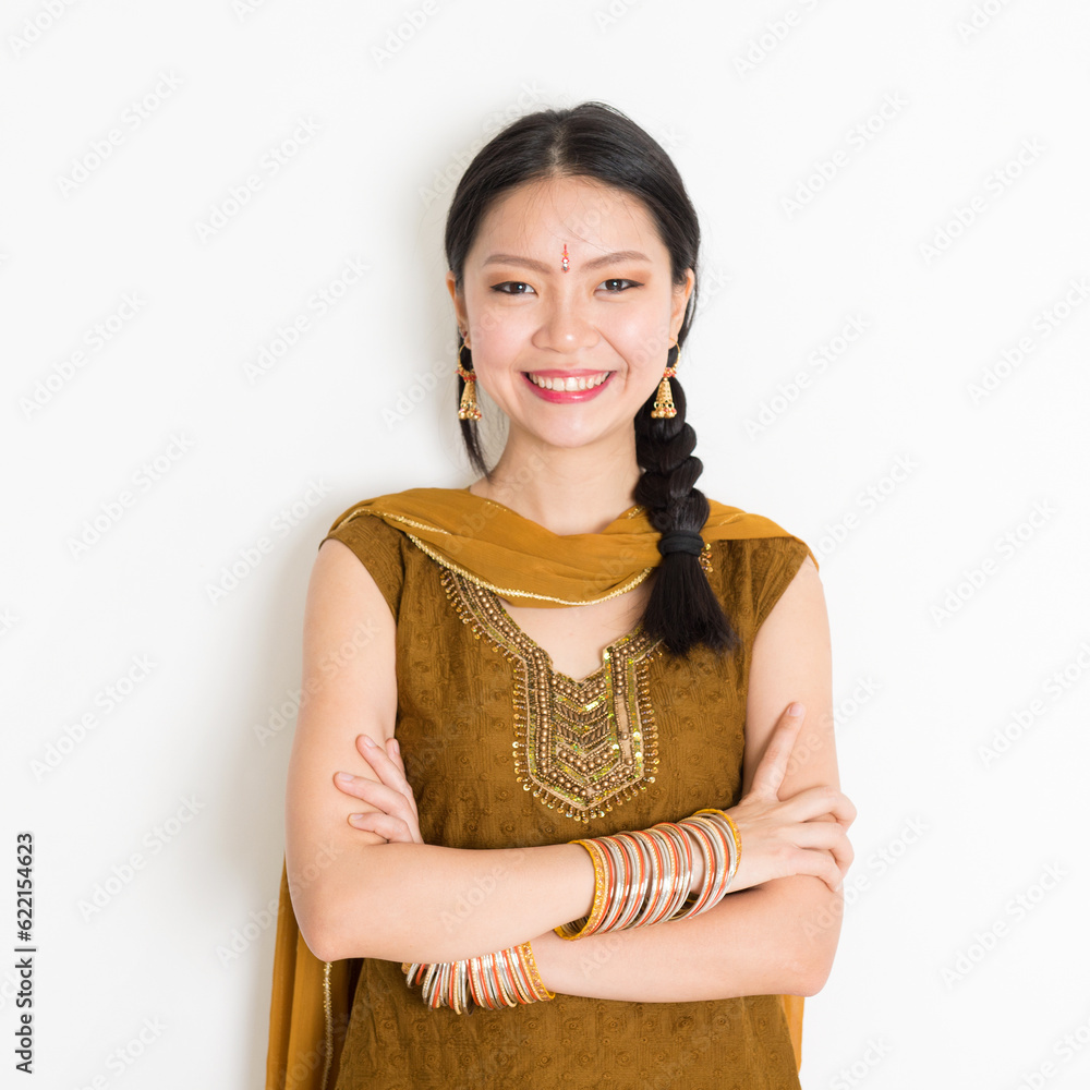 Portrait of arms crossed mixed race Indian Chinese female in traditional Punjabi dress smiling, standing on plain white background. Portrait of arms crossed mixed race Indian Chinese female in traditional Punjabi dress smiling, standing on plain white background.