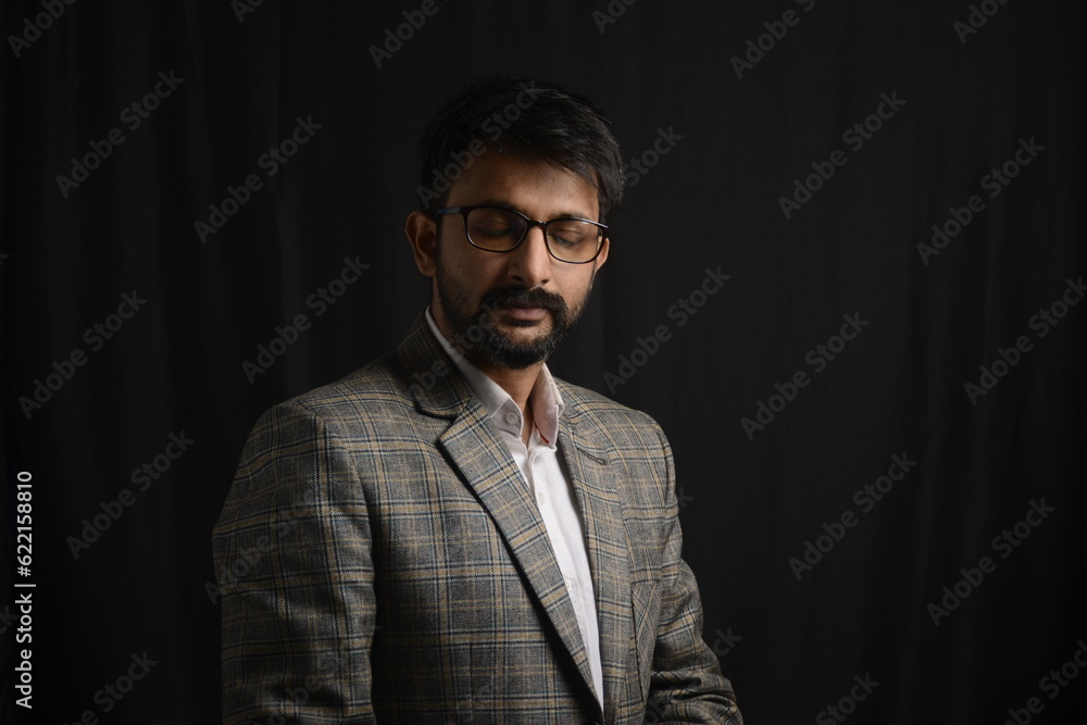 Portrait of happy corporate dressed up person in suit and wearing specs portraying different moods. Low key shoot of bearded office man well suited. Black background. Portrait of happy corporate dressed up person in suit and wearing specs portraying different moods. Low key shoot of bearded office man well suited. Black background.