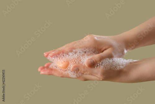 Hands with soap on color background