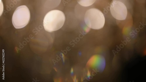 The bokeh of a crystal chandelier with crystals shimmers with bright lights. The ceiling light is brightly reflecting. Volumetric lamp with crystals rotates smoothly.