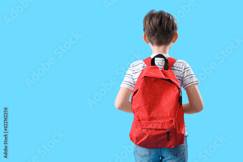 Fotografie, Obraz Little boy with schoolbag on blue background, back view