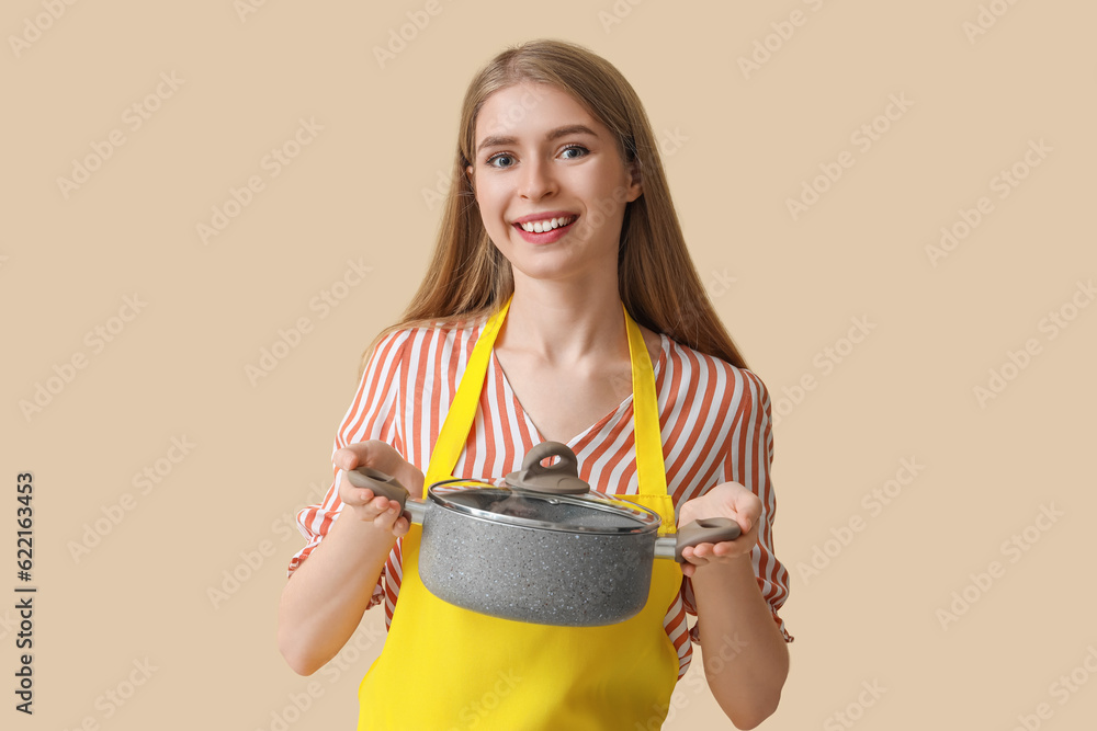 Young woman with cooking pot on beige background Young woman with cooking pot on beige background