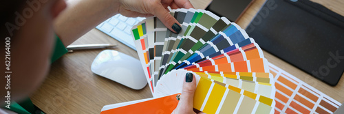 Female designer holding color samples and choosing color samples for projects.