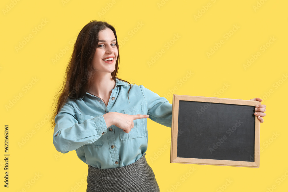 Female teacher pointing at chalkboard on yellow background Female teacher pointing at chalkboard on yellow background
