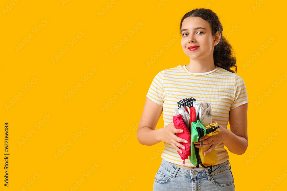 Female student with pencil cases on yellow background Female student with pencil cases on yellow background