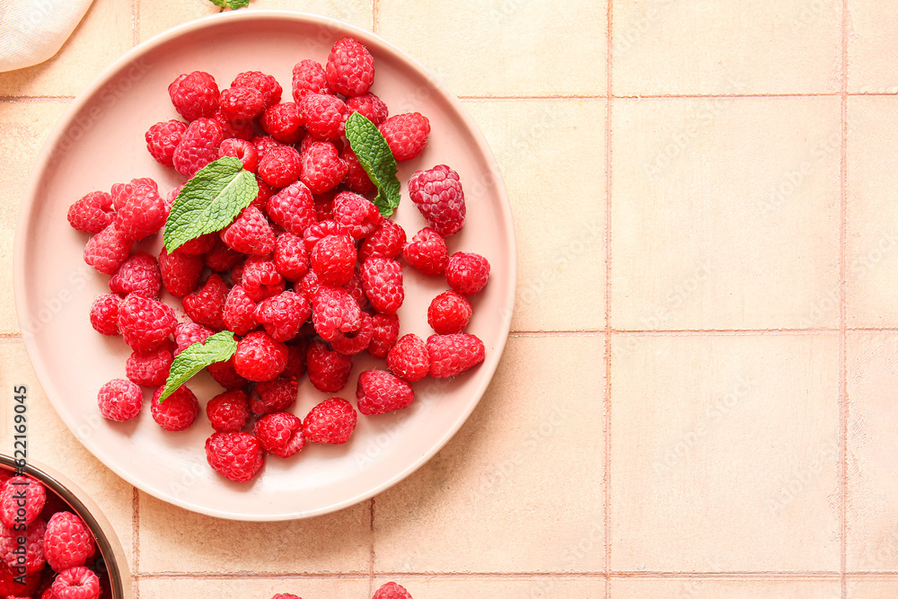 Plate with fresh raspberries and mint on pink tile background Plate with fresh raspberries and mint on pink tile background