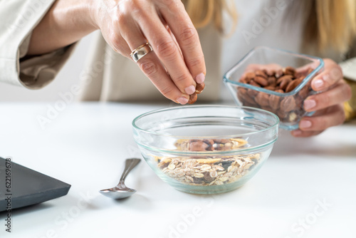 Healthy eating at work as a woman creates a nourishing bowl of muesli, enriched with almonds and hazelnuts. This photo captures the essence of balanced nutrition and workplace wellness. 