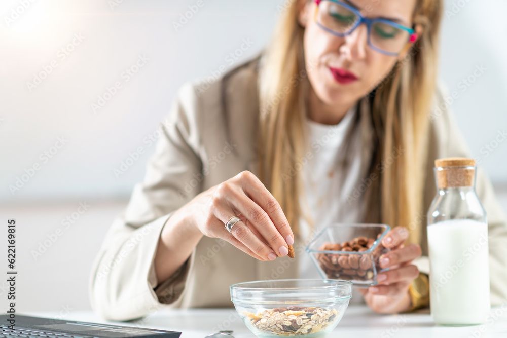 Healthy eating at work as a woman creates a nourishing bowl of muesli, enriched with almonds and hazelnuts. This photo captures the essence of balanced nutrition and workplace wellness. Healthy eating at work as a woman creates a nourishing bowl of muesli, enriched with almonds and hazelnuts. This photo captures the essence of balanced nutrition and workplace wellness.