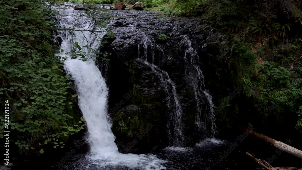 Crystal clear water flowing in small mountain river creating a small waterfall.