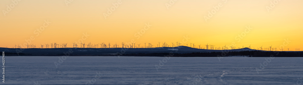 Markbygden Windmill park in the distance with Wind Turbines in motion rotating generating green electricity at sundown on a hill outside of Pitea, Northern Sweden. 