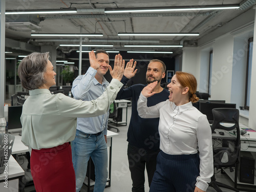 Four co-workers give a high five in the office.