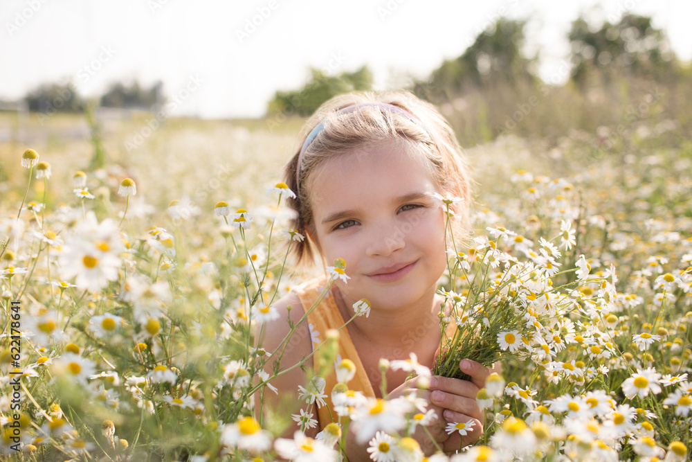 a little girl in a yellow dress sits on a chamomile field on a summer day a little girl in a yellow dress sits on a chamomile field on a summer day