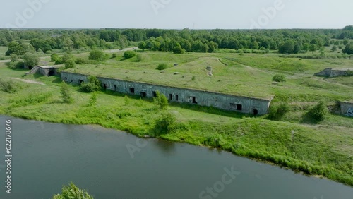 Aerial establishing view of abandoned historical concrete seaside fortification buildings, Southern Forts near the beach of Baltic sea in Liepaja, sunny summer day, ascending drone dolly shot photo