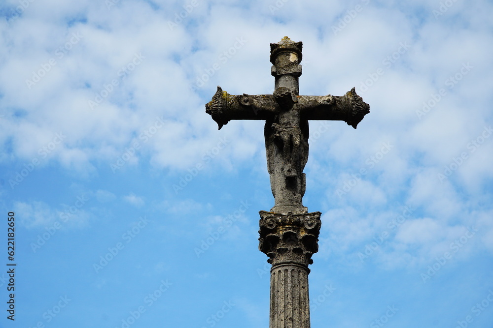Stone cross on a medieval column against the background of the sk