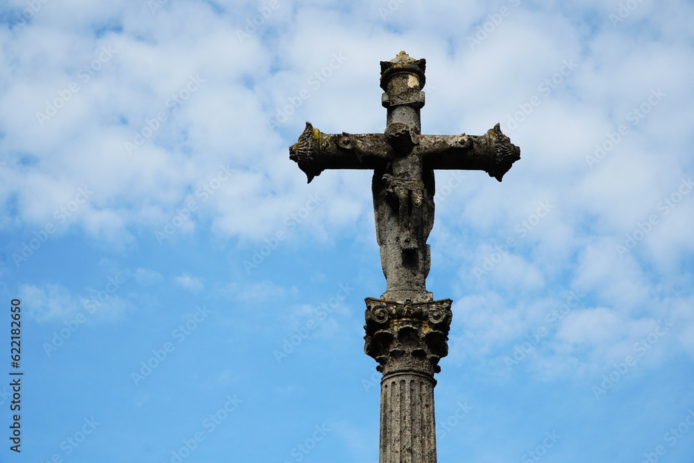Stone cross on a medieval column against the background of the sk Stone cross on a medieval column against the background of the sk