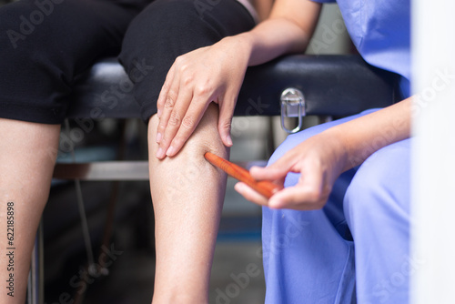physiotherapist massaging with wood stick on elderly woman legs,Reflexology spot thai massage