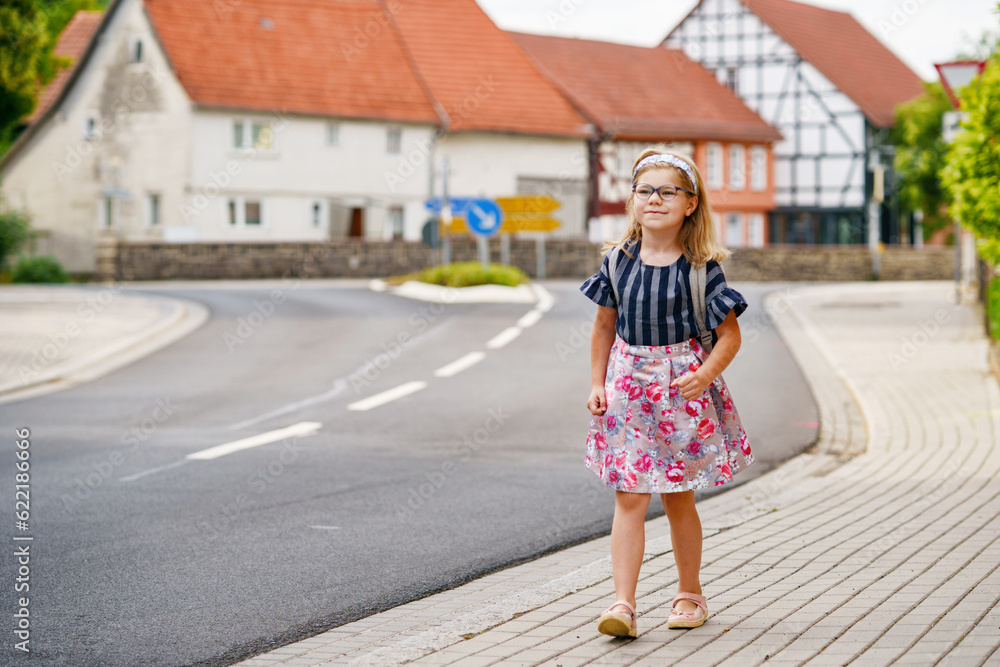 Little Preschool Girl on the Way to School. Healthy Happy Child Walking to Nursery School and Kindergarten. Smiling Child with Eyeglasses and Backpack on the City Street, Outdoors. Back to School.