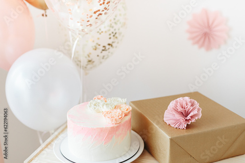Birthday celebration for girl at home light pink and gold colors. cake with flowers, balloons, gift