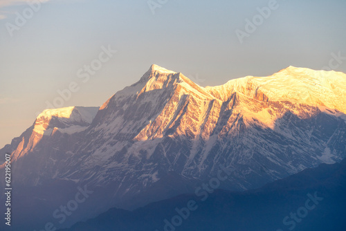 Machhapuchhre Peak, the sunrise area of annapurna base camp, Nepal, is a very beautiful peak of the Himalayas. snow capped peaks photo from a distance The red-orange morning sun shines brightly.