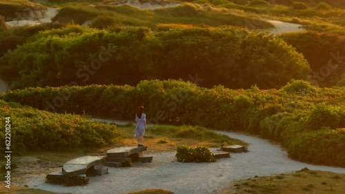 Drone orbit around woman with arms out cinematic sunset light, dunes of Katwijk photo