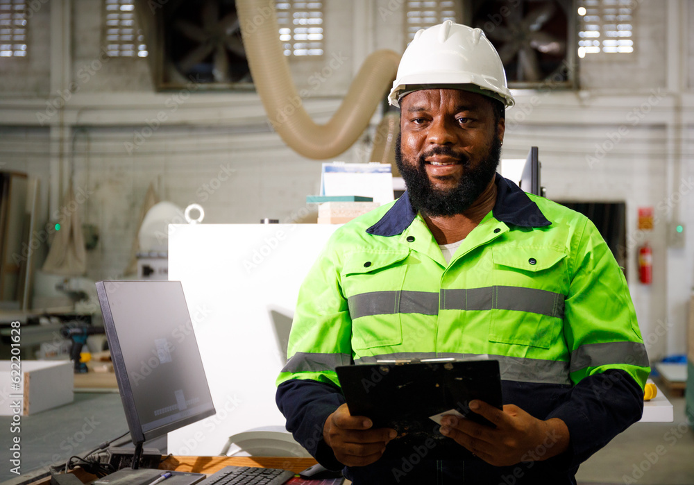 Portrait. African male engineer using a tablet computer. The background is a CNC cutting machine in the factory. Portrait. African male engineer using a tablet computer. The background is a CNC cutting machine in the factory.