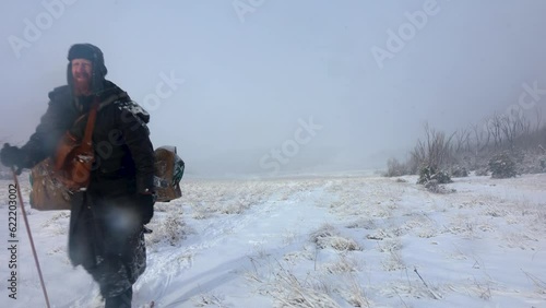A man dressed as a polar explorer carries a swag in a snow storm blizzard through the mountains of Australia. photo