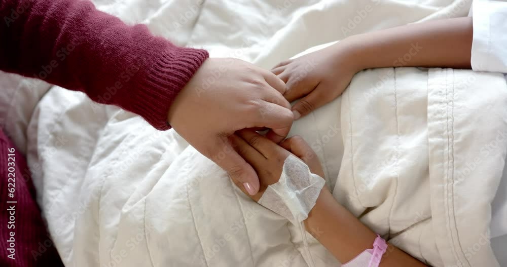 Holding hands of african american mother and daughter lying in hospital bed, slow motion Holding hands of african american mother and daughter lying in hospital bed, slow motion