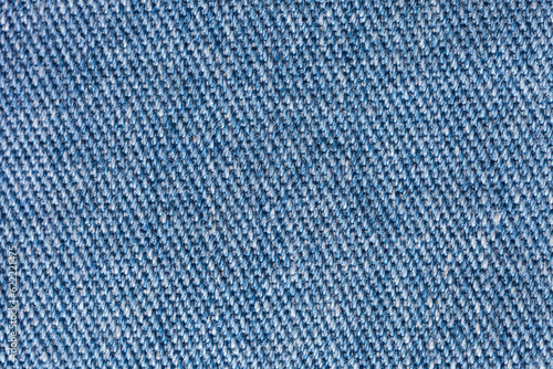Close-up of blue denim. Gray and blue textile background of intertwined natural cotton threads. Basis for sewing jeans, shirts, always fashionable denim, light clothing. Flat lay, macro, copy space