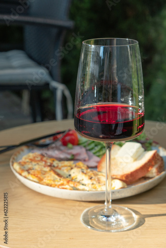 A glass of wine and plate with omelette, turkey and vegetables