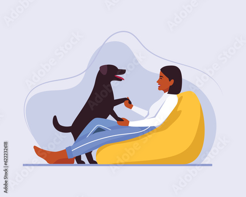 dark-skinned girl with short hair sits on a bean bag chair with a dog