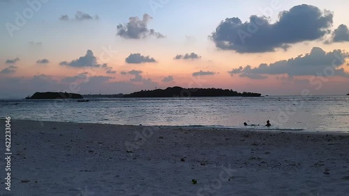 Romantic couple of tourists bathe at sunset in Maldives bay photo