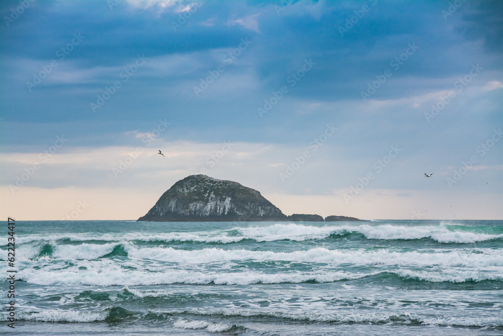 Sunset over Muriwai beach. Angry waves crashing onto the empty beach. Auckland, New Zealand Sunset over Muriwai beach. Angry waves crashing onto the empty beach. Auckland, New Zealand