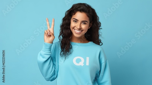 Young happy latin woman student showing ok hand okay sign winking isolated on blue background. Smiling female model advertising sale offer presenting promotion recommending discounts, generative ai