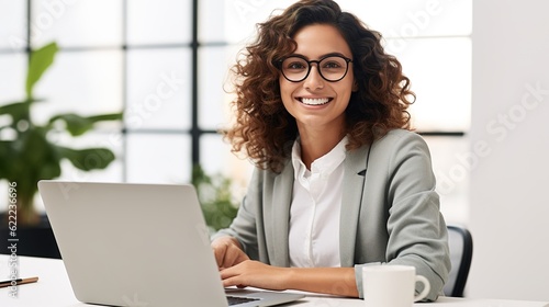 Smiling female professional executive using computer in corporate office looking at camera photo