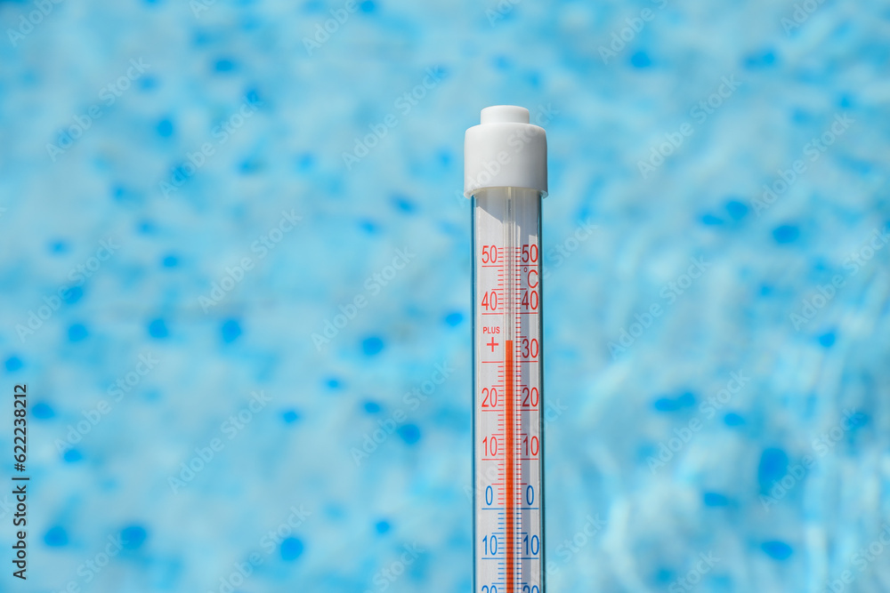 Termometr pokazujący wysoką temperaturę na tle basenu ogrodowego - obrazy, fototapety, plakaty 