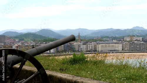 Close up shot of historic artillery gun on urgull mountain with sandy beach and skyline of San Sebastián in background photo