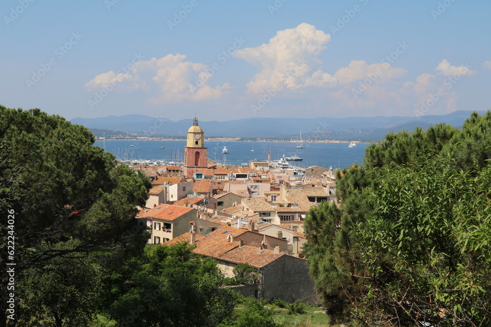 panoramic view over the red tiled rooftops of Saint Tropez and the azur water of the bay in the distance