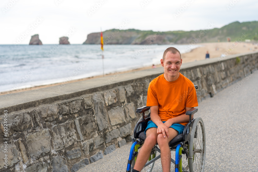 Fototapeta premium A disabled person in a wheelchair by the beach, having fun in summer