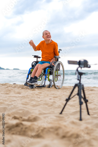 Portrait of a disabled person in a wheelchair recording a video by the beach © unai