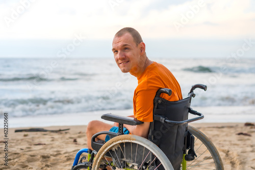 Portrait a disabled person in a wheelchair on the beach enjoying the freedom of the sea and nature