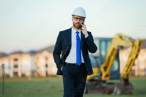 Builder engineer or civil engineer worker at a construction site. Engineer worker in suit and helmet at construction site. Supervisor construction manager near excavator. Renovation building concept.