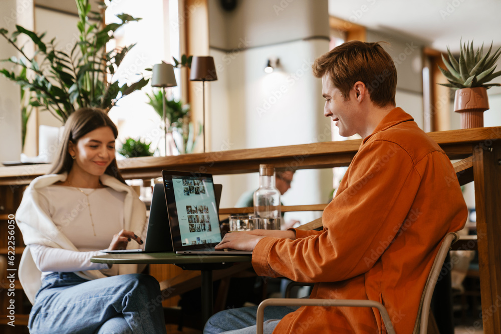 Fototapeta premium Couple working on laptops while sitting in cafe