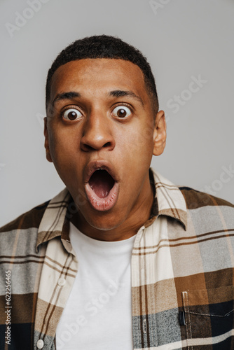 Young shocked man expressing surprise with mouth open while isolated