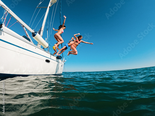 Happy friends diving from sailing boat into the sea - Travel and summer vacation concept - Soft focus on blond girl face © DisobeyArt