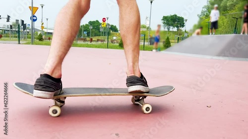 The skateboarder performs a frontside smith grind to fakie trick on a rail in the skatepark photo