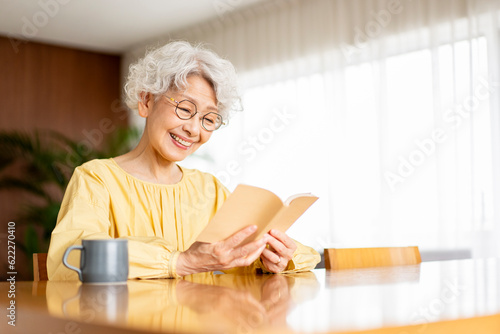 Obraz w ramie 老眼鏡をかけて本を読んでいる日本人シニア女性
