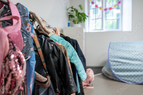 A lot of Children clothes hanging on rack in kindergarten room