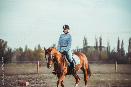Young woman athlete rides a horse. Jumping training in the spring in the field. © sergo321