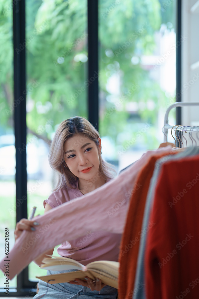 Portrait Of Asian Female Owner Of Fashion Store Checking Stock In Clothing Store With using notebook successful happy smile at small business, sme or ecommerce concepts Portrait Of Asian Female Owner Of Fashion Store Checking Stock In Clothing Store With using notebook successful happy smile at small business, sme or ecommerce concepts